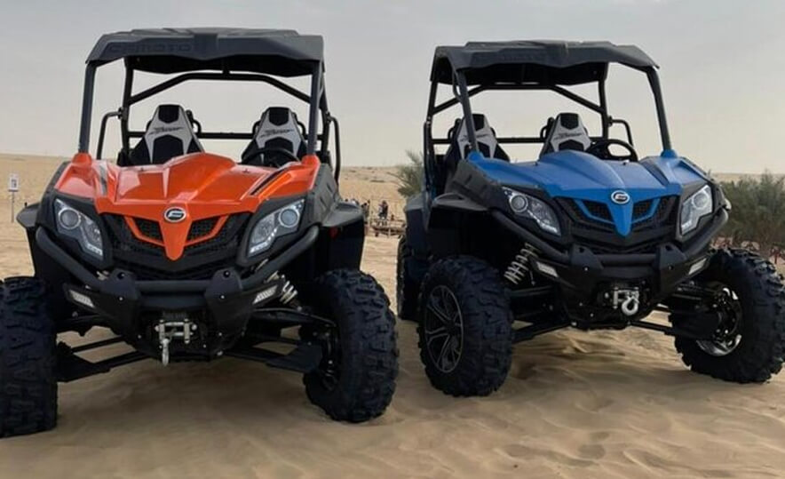 Group riding Polaris 4-seater buggy across Dubai dunes